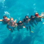 TauchKurs Mexiko: Gruppe von Tauchern taucht in klares Wasser unter einem Korallenriff.